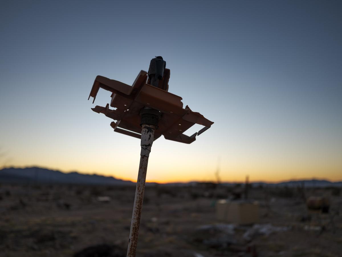 Mysterious object silhouetted against dawn sky in desert landscape.