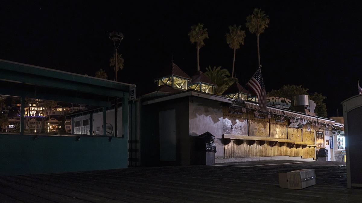Night view of Eric's On The Pier restaurant in multi-colored light with prominent American flag.