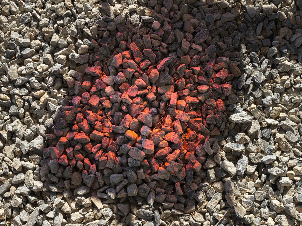 Gravel bed crossed by shadows with pink-tinted area in middle.