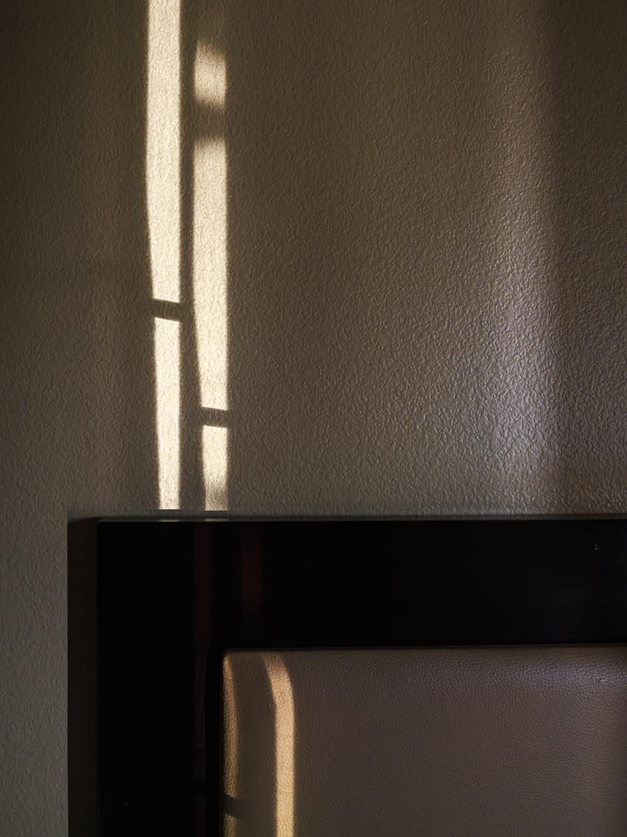 Vertical stripes of light crossing bed frame.