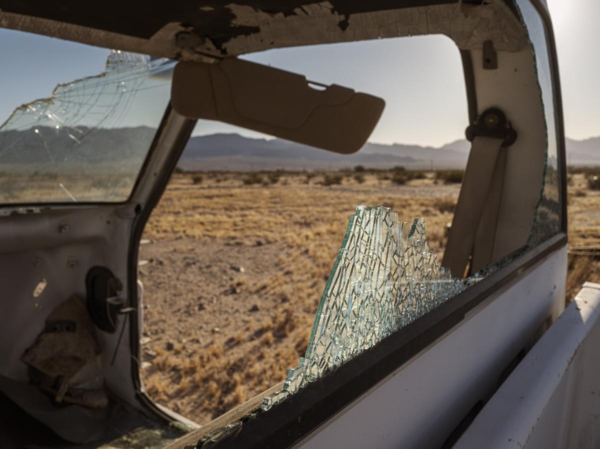 Abandoned truck in desert landscape. Its windows are broken, but some pieces cling together in their original location.