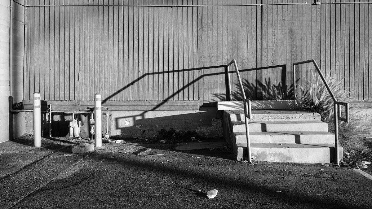 A crooked concrete staircase leads to a blank wall.